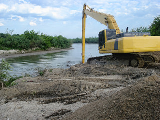 Yellow excavator on river