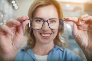 Portrait of cheerful female client hanging out glasses while looking at camera. Eye care concept