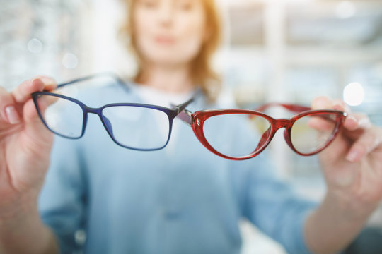 Close up female hands holding eyeglasses in glasses shop. Ophthalmology concept