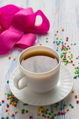 Cup of Coffee and Multicolored Decoration Sweets, Pink Tape on a Wooden Table