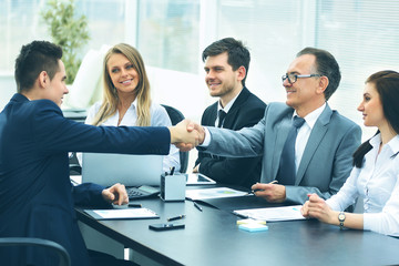 Business meeting at the table and handshake of business partners