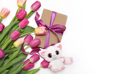 Bouquet  pink tulips and gift diary with festive ribbon, soft toy on white table top view with copy space for message. Greeting card for Valentine's Day, Woman's Day and birthday holidays.