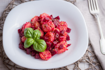 Home-made gnocchi and beet root on white plate
