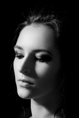 Studio portrait of a girl with professional make-up on closed eyes in fashion style on a black background close-up