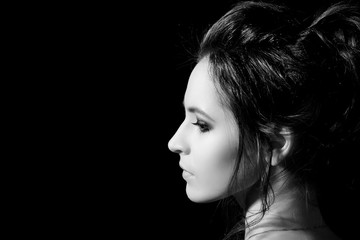 Portrait in a profile of a girl with a professional make-up on a black background close-up