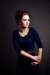 Girl with hair and makeup in blue dress posing on black background in fashion style