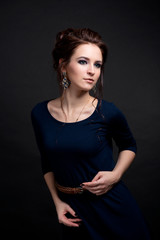 Girl in blue dress and with make-up and hairstyle posing on black background