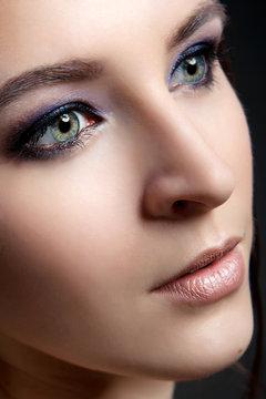 Portrait of a stylish girl with a professional make-up and clean skin on a black background close-up