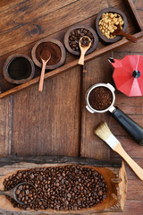 Freshly ground coffee beans in a metal filter and coffee beans with red kettle on the side.