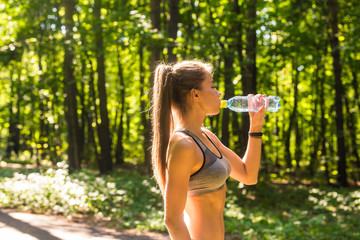 Fitness beautiful woman drinking water and sweating after exercising on summer hot day in park. Female athlete after work out.