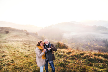 Fototapeta premium Senior couple on a walk in an autumn nature.