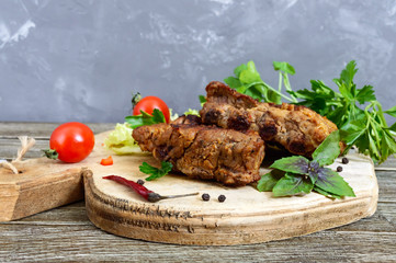 Fried pork ribs with greens on a cutting board.