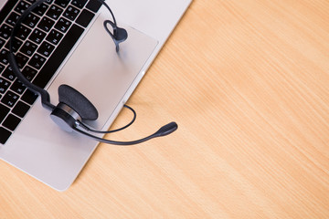 Black headset for operator with laptop computer on wood desk