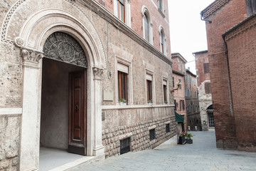 Fototapeta na wymiar Old arch door in building facade in Siena