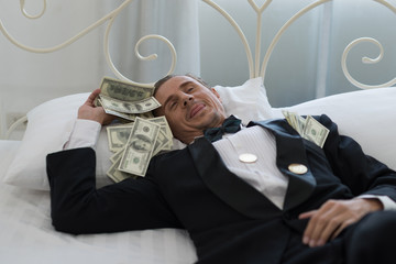 Young Businessman with happy, smile on the bed. who are successful in business and many banknote dollars money. business success concept.