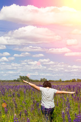 happy plus size woman enjoying summer in violet lupine field at blue sky at sunset. Plus size model. Concept - freedom from complexes.