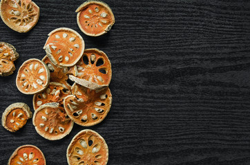 Dried herbs and dried bael fruit, Top view of bael dry on the wooden floor, Slices of bael fruit for make bael juice on the dark table.