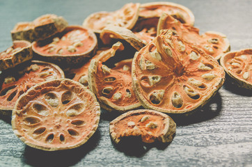 Dried herbs and dried bael fruit, Close-up of bael dry on the wooden floor, Many of slices of bael fruit for make bael juice on the dark table.