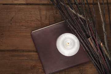 An overhead photo of a handmade broom with a candle, a grimoire, and copy space