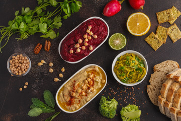 Vegan food background. Vegetarian snacks: hummus, beetroot hummus, green peas dip, vegetables. Top...