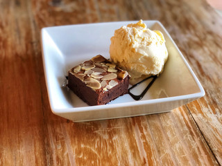 rownie with ice cream in white  Square plate on the wooden table. Natural light and copy space . Delicious and unhealthy menu.