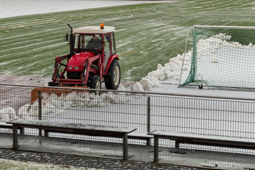 Red tractor removes snow from the football field