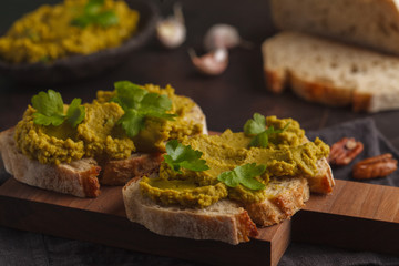 Green peas spread on sandwiches on a wooden board. Healthy vegetarian food concept.