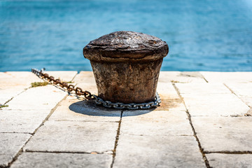 Naklejka premium Old rusty steel mooring bollard pole on a pier.