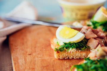 bruschetta, appetizer, canapes: fish tuna and spinach on toast of white bread, with egg on wooden Board