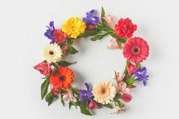 top view of floral wreath made of beautiful colorful flowers and green leaves on grey