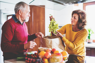 Senior couple unpacking fruit in the kitchen.