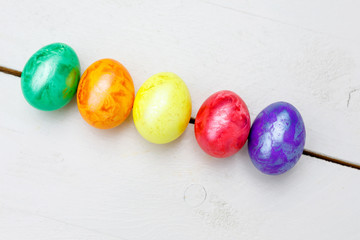 Easter eggs on wooden background. Colorful eggs in different colors - red, yellow, orange, purple and green.