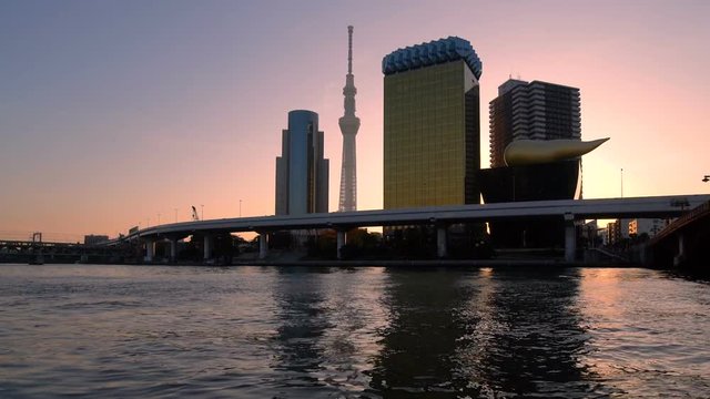 Sunrise at Tokyo city skyline shot from Sumida river in the city center of Tokyo , Japan. Realtime footage.