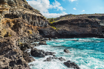 The blue waters of the Atlantic Ocean flowing into rocky cove off the coast of Tenerife.  rocky shores of Canary Islands.