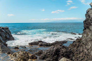 The blue waters of the Atlantic Ocean flowing into rocky cove off the coast of Tenerife.  rocky shores of Canary Islands.