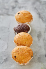 Tasty muffins arranged in pattern on light textured background, close-up, shallow depth of field, selective focus.