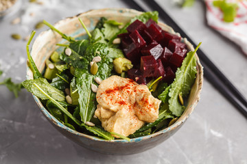 Green vegan salad with kale, beetroot, cucumber, sunflower seeds with hummus dressing. Healthy vegetarian detox food concept.