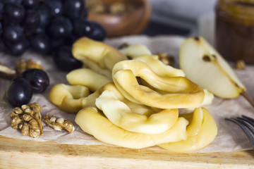 String Cheese, honey, grapes, pears and nuts on wooden board on kitchen