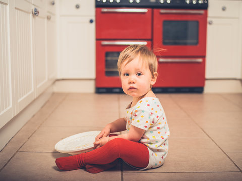 Little boy on kitchen floor with salad spinner