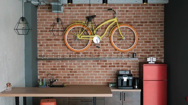 a real modern interior in loft style. In the kitchen there is a bar, a refrigerator and a decorative bicycle