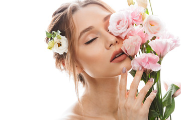 Feminine half naked lady 20s holding bouquet of beautiful eustoma flowers with closed eyes, isolated over white background