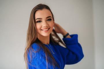 Beautiful brunette girl with a lovely smile in a blue blouse posing for a photographer and showing her makeup