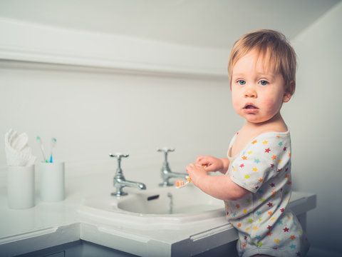 Little boy brushing his teeth by the sink