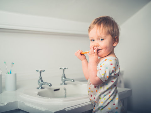 Little boy brushing his teeth by the sink