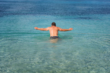 Young handsome man diving at the Ionian sea, Zakynthos Island, Greece.