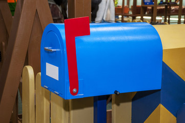 Vintage blue mail box with red raised flag and white blank label for inscription