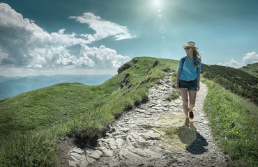 Fototapeta premium Woman hiking in mountains at sunny day time.