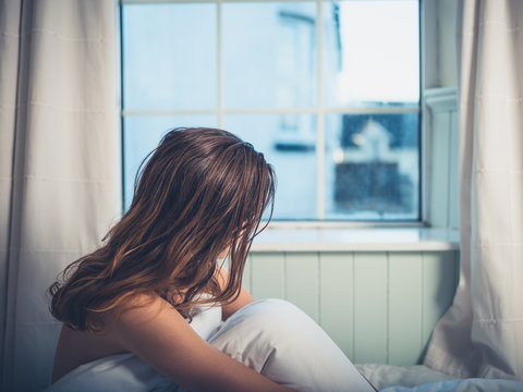 Young woman in bed looking out the window