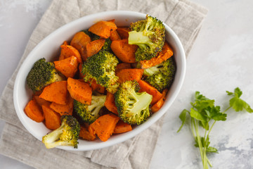 Baked broccoli and sweet potato with spices in white dish, top view. Vegan Healthy Food Concept.