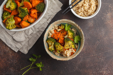 Brown rice with baked broccoli and sweet potato, dark background, top view. Healthy vegan food concept.